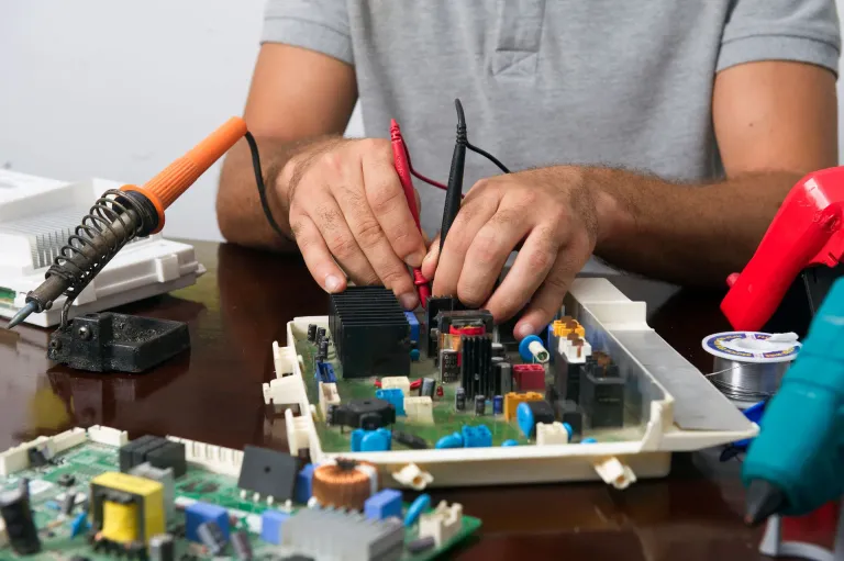 Dłonie technika mierzącego multimetrem moduł elektroniczny na stole warsztatowym