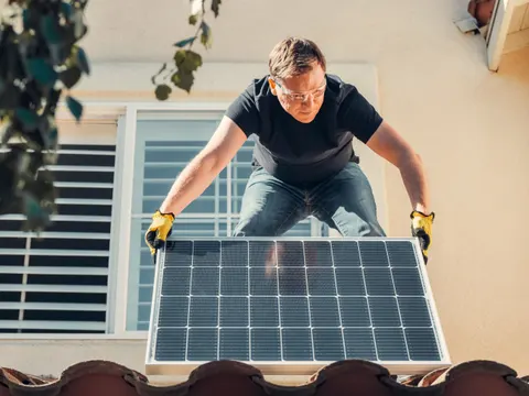 Instalator montujący panel fotowoltaiczny na dachu domu