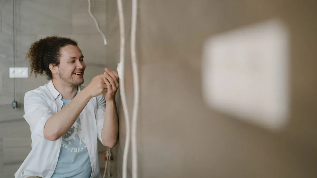 Uśmiechnięty elektryk montujący gniazdko podczas wykańczania mieszkania